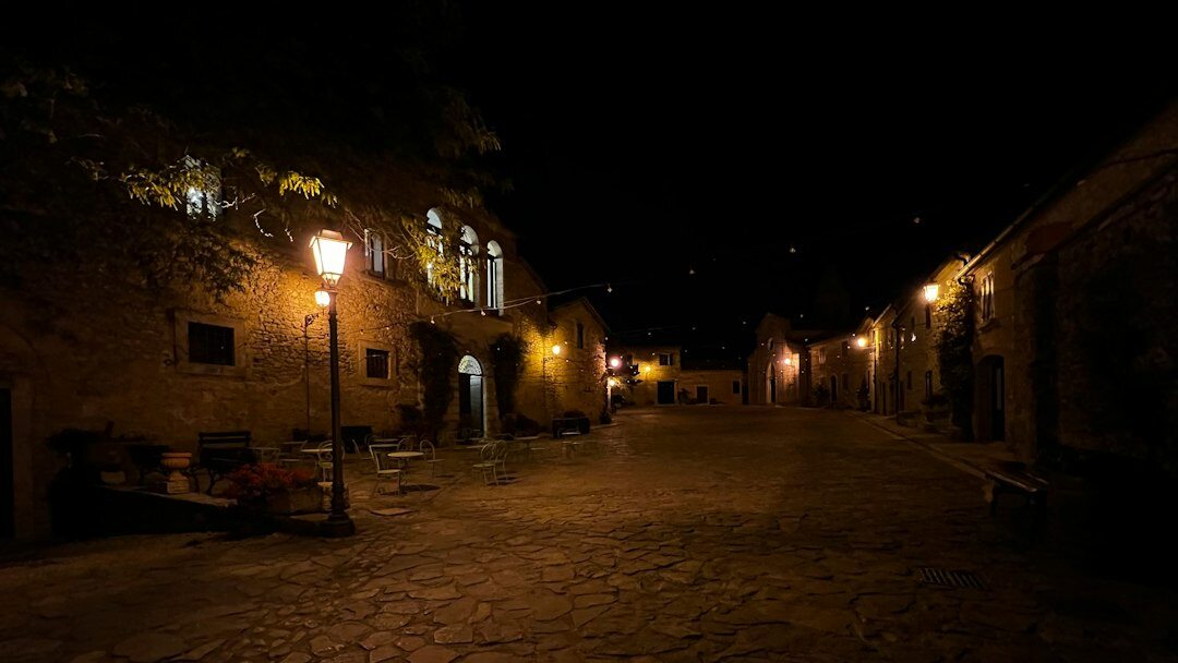 Foggy cobblestone street in an old European town at night with a single glowing lamp
